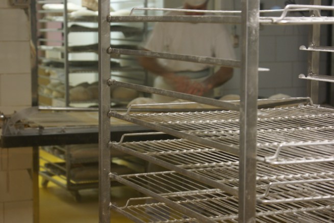Baker slashing the tops of risen dough before sliding them into the oven; Baluard bakery, Barceloneta. June 20, 2012.
